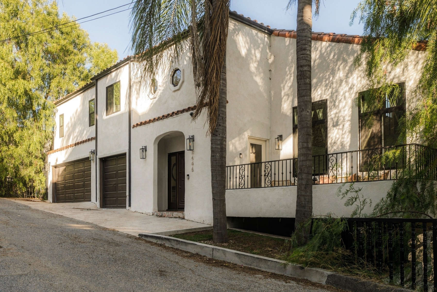 Street front of 3646 Potosi Avenue, a white stucco Mediterranean with a red tile roof and a three-car garage